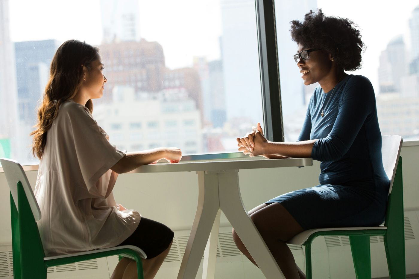 Two women in a coaching conversation by a city window